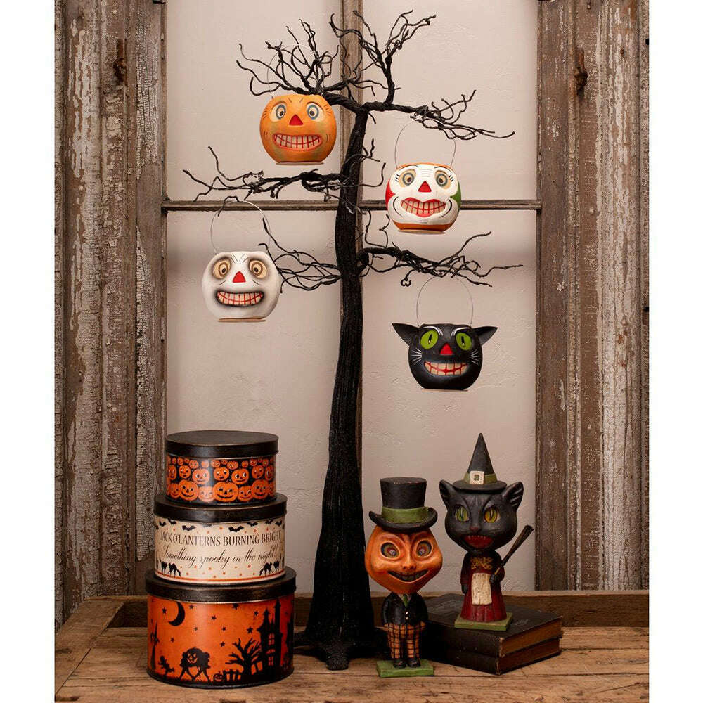 1. Halloween nesting tins displayed alongside vintage-inspired seasonal decorations on a rustic shelf.