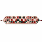 A festive Christmas-themed table runner with a repeating pattern of red, green, and cream holiday motifs, finished with red tassels on both ends.