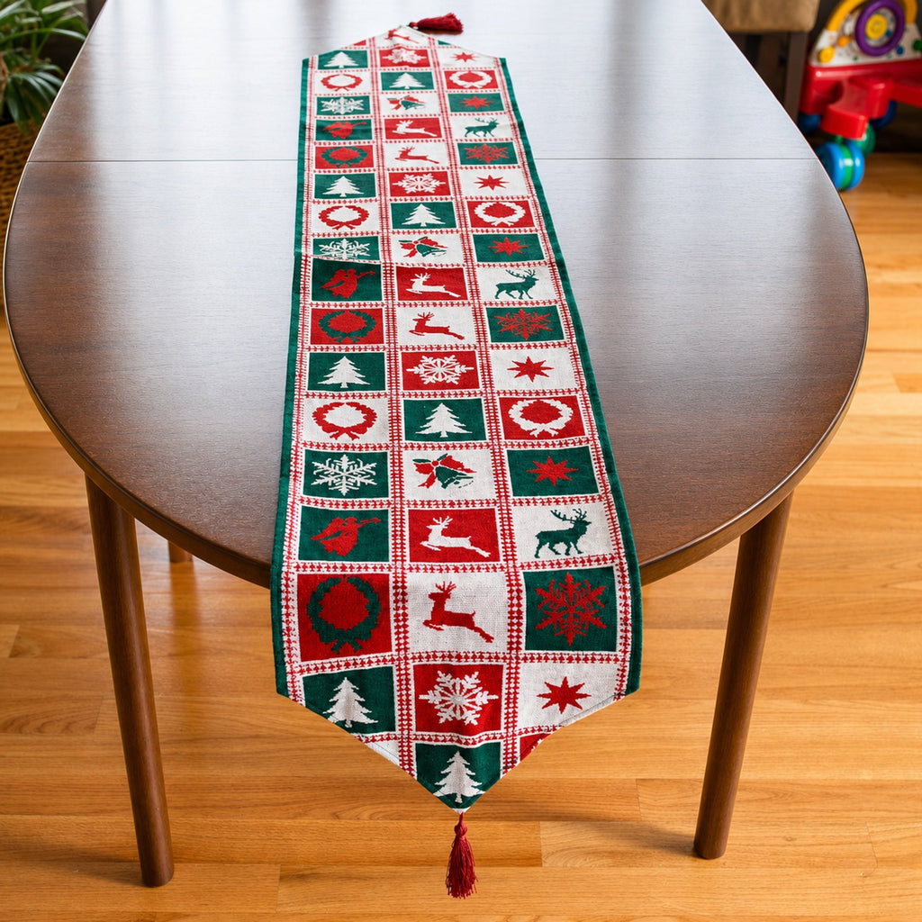 A festive Christmas table runner with a patchwork design of red, green, and white holiday motifs, draped over a dark wood oval table on a light wood floor.