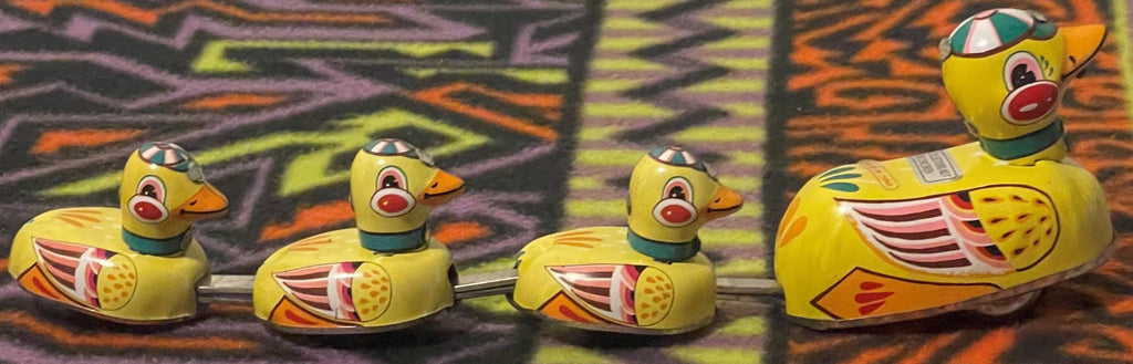 Colorful vintage tin duck family toy displayed in a row
