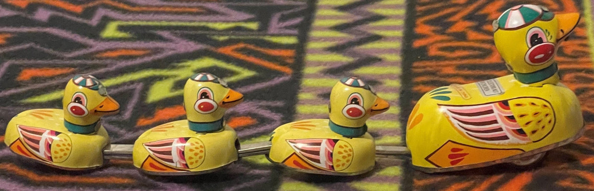 Colorful vintage tin duck family toy displayed in a row