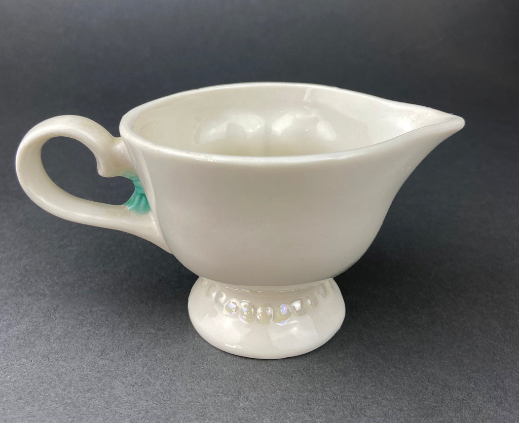 Back of White vintage Bailey’s ceramic creamer shaped like a smiling face with one eye winking, a blue bow, and a small handle.