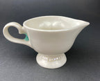 Back of White vintage Bailey’s ceramic creamer shaped like a smiling face with one eye winking, a blue bow, and a small handle.