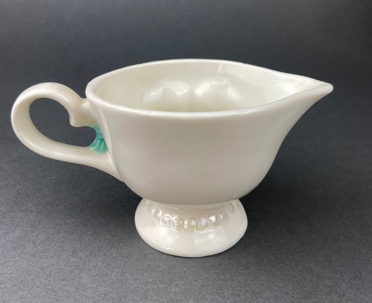 Back of White vintage Bailey’s ceramic creamer shaped like a smiling face with one eye winking, a blue bow, and a small handle.