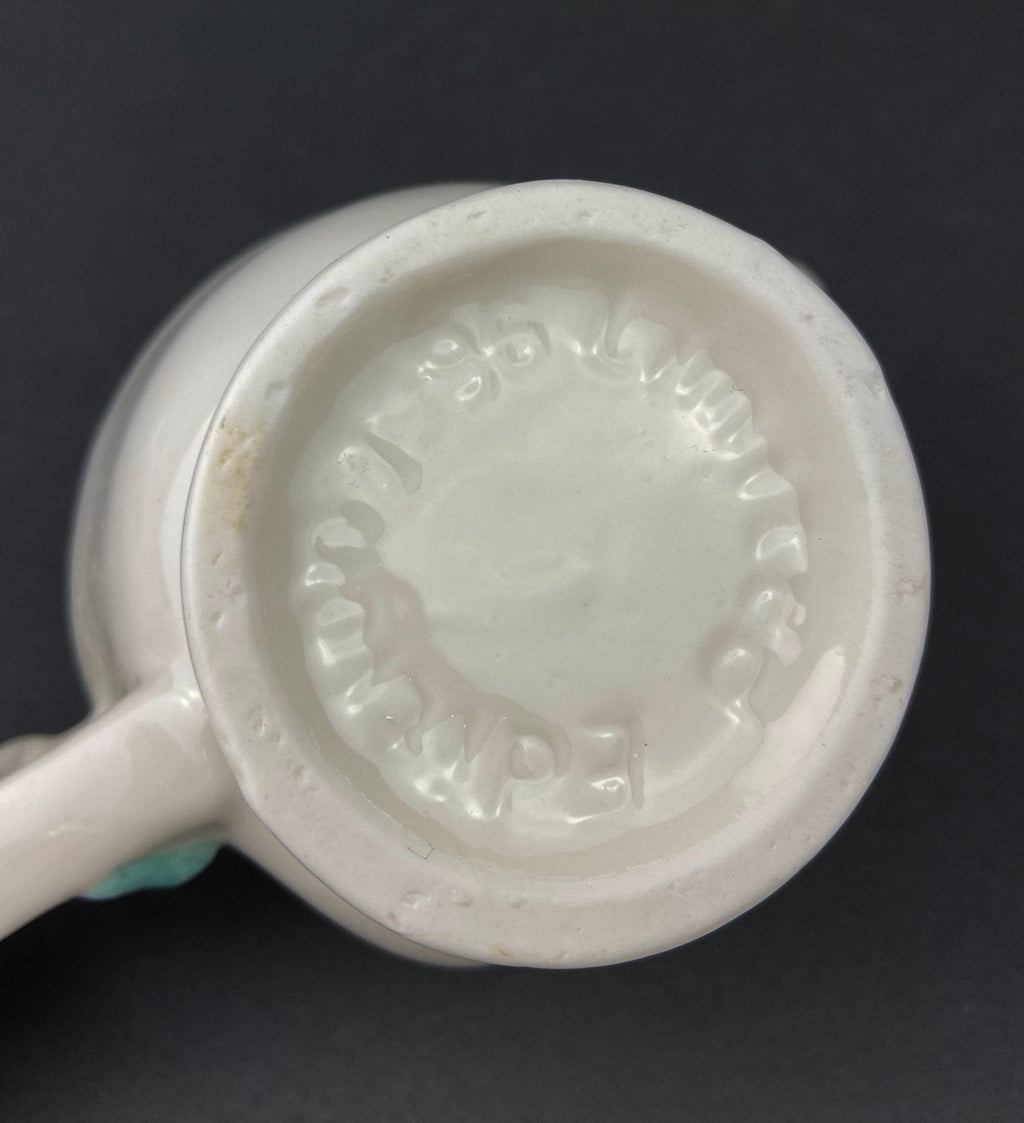 bottom White vintage Bailey’s ceramic creamer shaped like a smiling face with one eye winking, a blue bow, and a small handle.