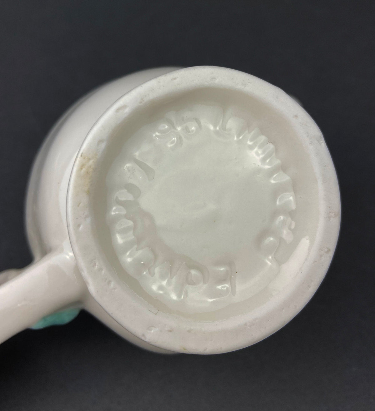 bottom White vintage Bailey’s ceramic creamer shaped like a smiling face with one eye winking, a blue bow, and a small handle.