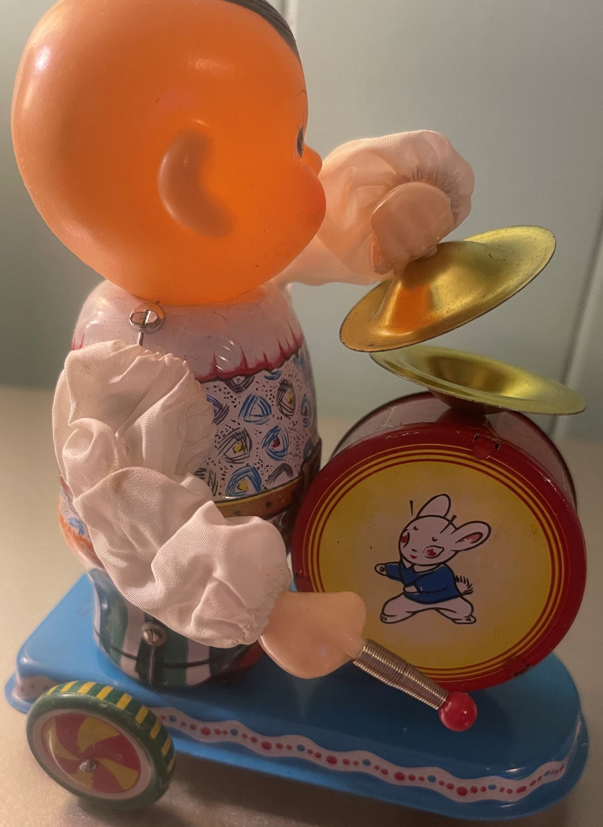 Close-up of the vintage wind-up drummer toy showing its painted drum and colorful base