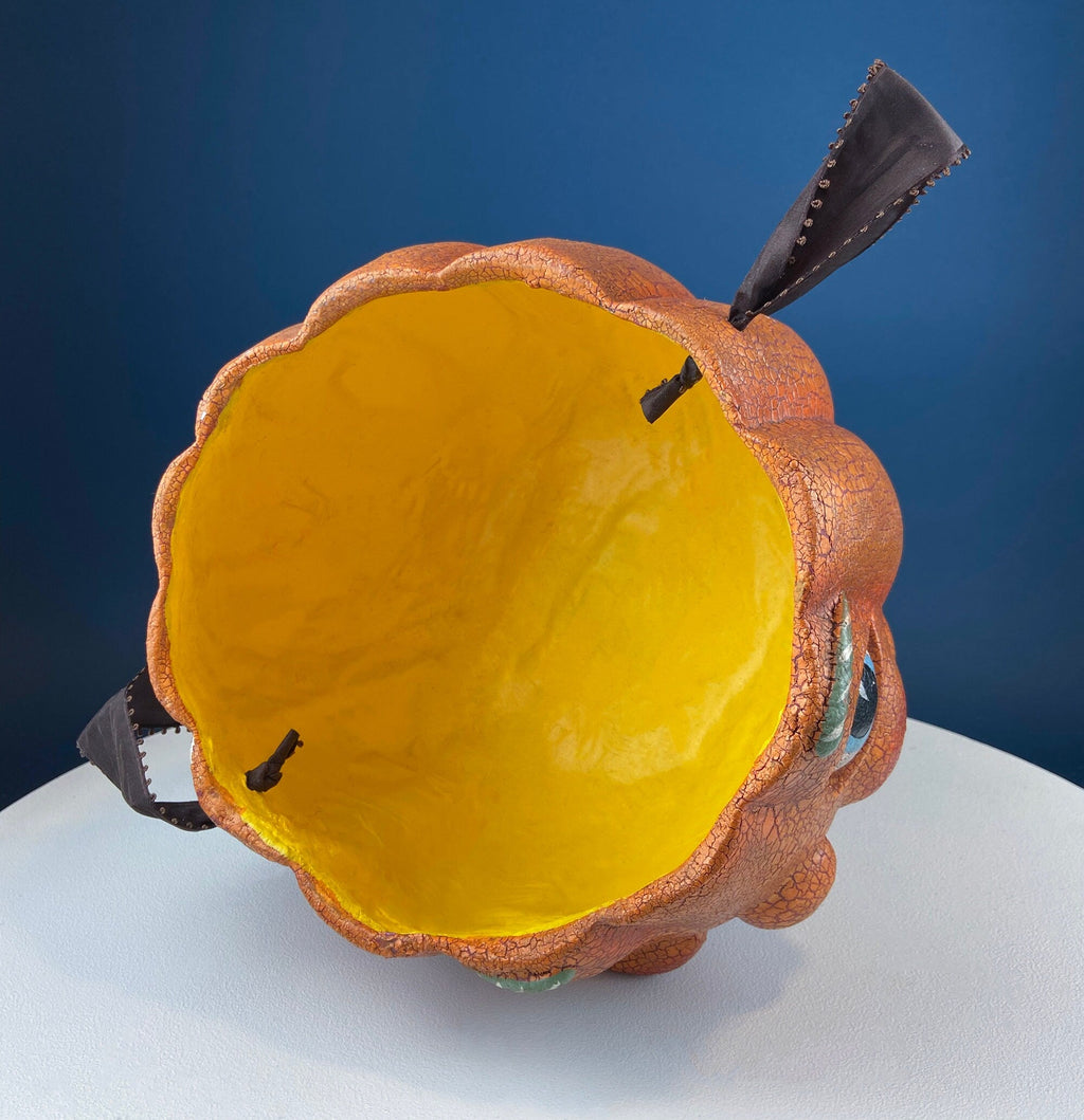 Vintage orange papier-mâché jack-o’-lantern basket with a hand-painted smiling face, blue eyes, and a crackled finish.