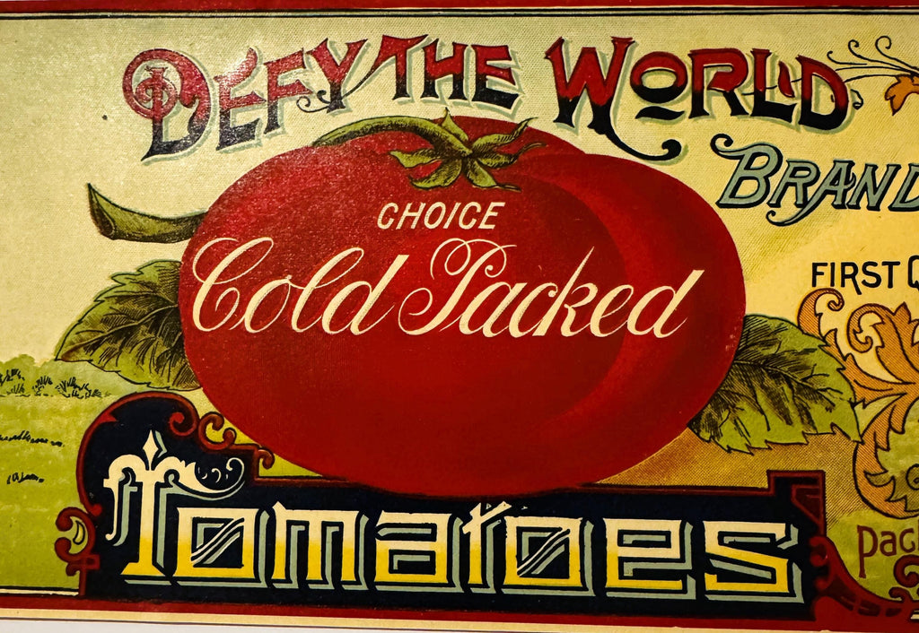 Large red tomato and vintage typography on antique Defy The World can label