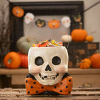 Mr. Albert Skully skull bucket filled with wrapped Halloween treats and displayed among pumpkins and autumn decorations.