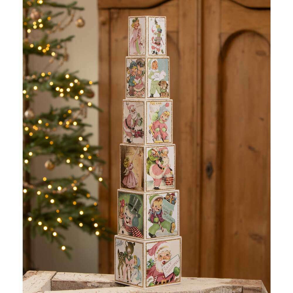 Tall arrangement of vintage-inspired Christmas postcard nesting blocks beside Christmas tree