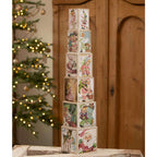 Tall arrangement of vintage-inspired Christmas postcard nesting blocks beside Christmas tree