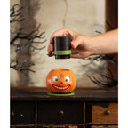 Hand lifting the removable top hat from the Smiling Pumpkin Container to reveal its hidden compartment.