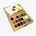 Open bamboo watercolor paint box displaying 18 colorful paint pans and a removable mixing tray