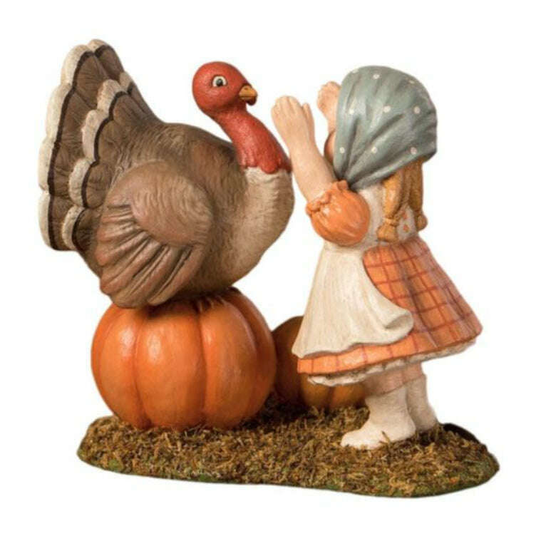 Trudy with Turkey Thanksgiving figurine by Bethany Lowe Designs, showing a little girl in a bonnet and apron reaching up to hug a turkey standing on a pumpkin.