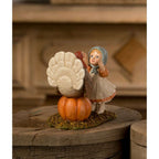 Rear view of Trudy with Turkey Thanksgiving figurine, showing the turkey’s tail feathers and Trudy’s blue bonnet.