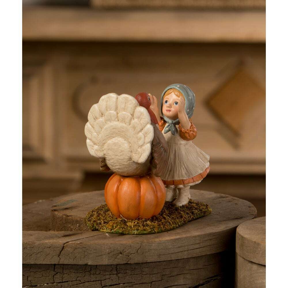 Rear view of Trudy with Turkey Thanksgiving figurine, showing the turkey’s tail feathers and Trudy’s blue bonnet.