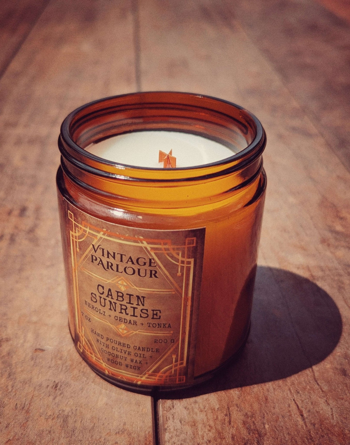 Vintage Parlour Cabin Sunrise wooden wick candle in an amber glass jar on a rustic wooden surface