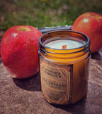 Vintage Parlour Old Orchard wooden wick candle in an amber glass jar styled with fresh red apples