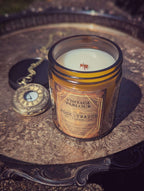 Vintage Parlour Pocketwatch wooden wick candle in an amber glass jar displayed beside an antique pocket watch