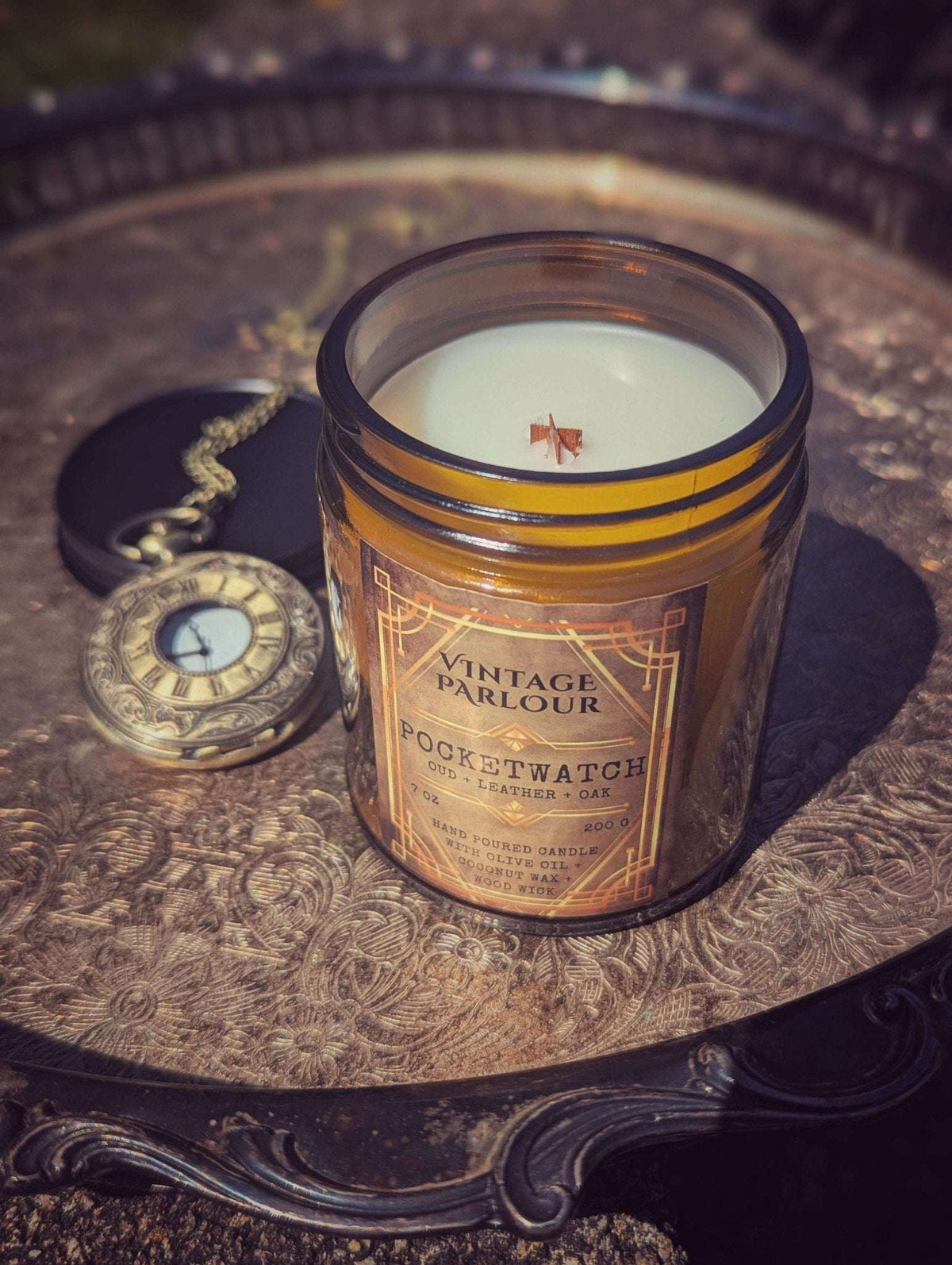 Vintage Parlour Pocketwatch wooden wick candle in an amber glass jar displayed beside an antique pocket watch